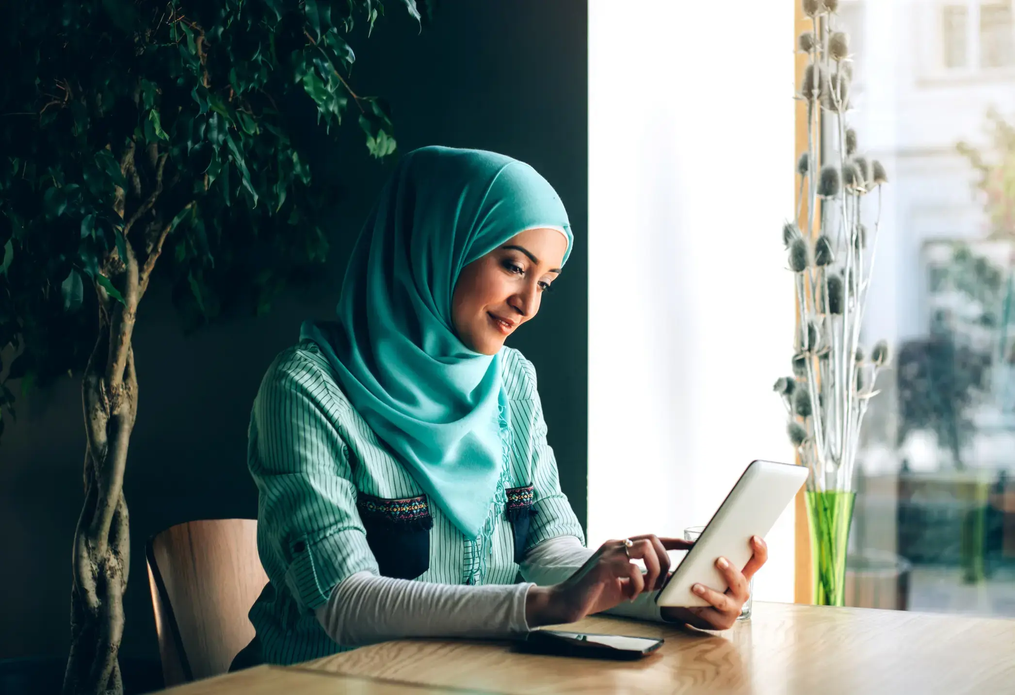 A veiled woman holding a tablet and scrolling through it