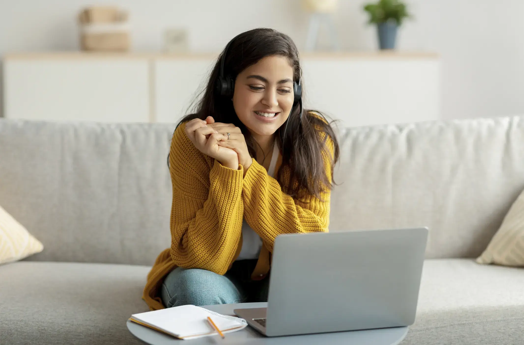 A woman talking on her laptop through a video call, wearing a headset.